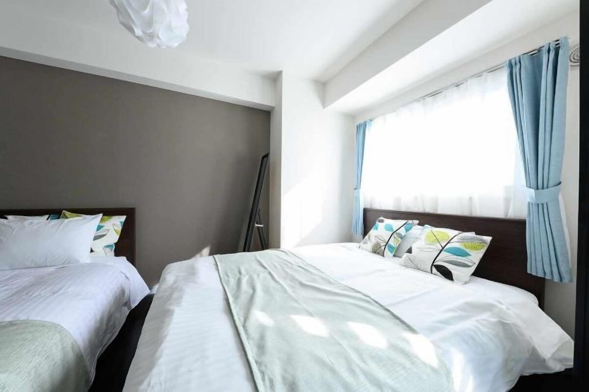 Een hotelkamer met twee bedden, een raam met gordijnen en een flatscreen-televisie.