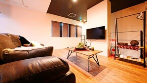 Una sala de estar moderna con un sofá de cuero, una mesa de centro de madera y un televisor de pantalla plana montado en la pared.