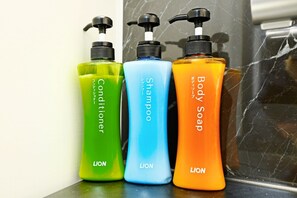 Three bottles of LION brand personal care products: conditioner, shampoo, and body soap, arranged on a marble surface.