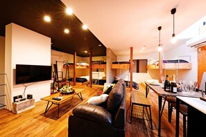 Un espace de vie compact comprenant des lits superposés, un téléviseur à écran plat, un canapé et une table à manger.