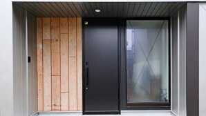 Una entrada de edificio moderna con un panel de madera, una puerta negra y una puerta de cristal.