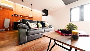 Una sala de estar moderna con sofá de cuero, piso de madera y una mesa de comedor.
