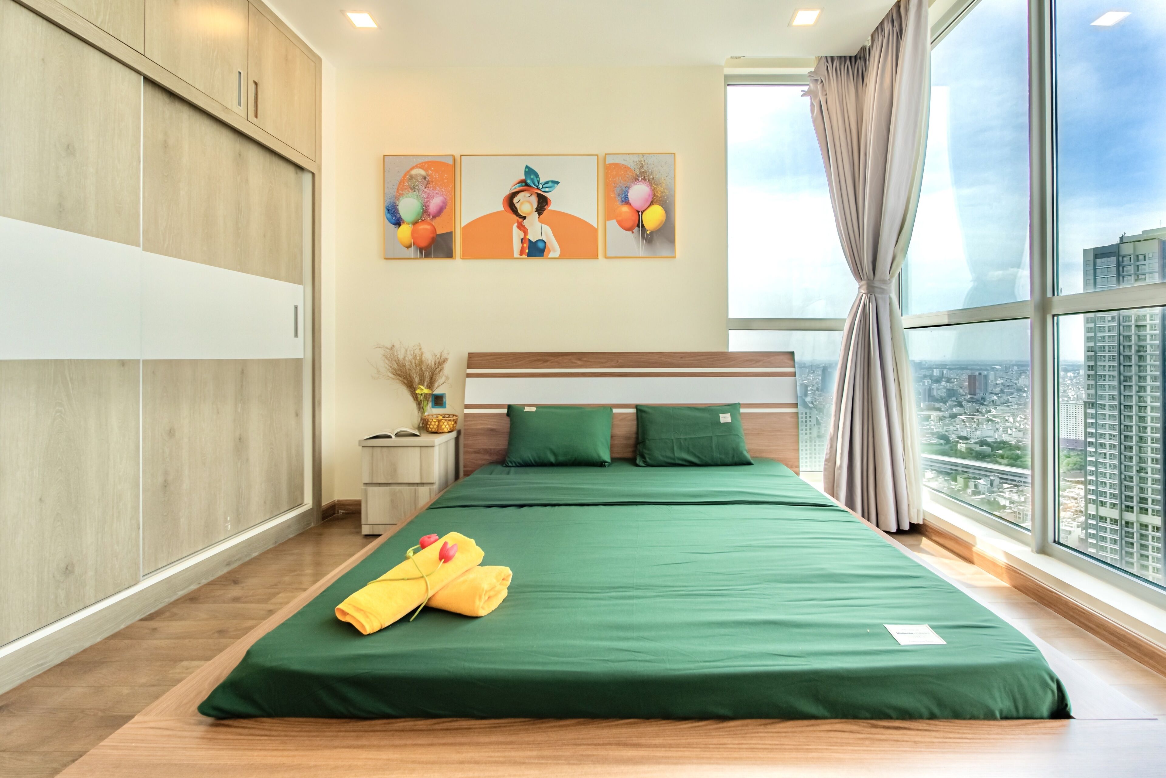 Habitación de hotel con una cama grande, ropa de cama verde, vistas a la ciudad y un armario de madera.