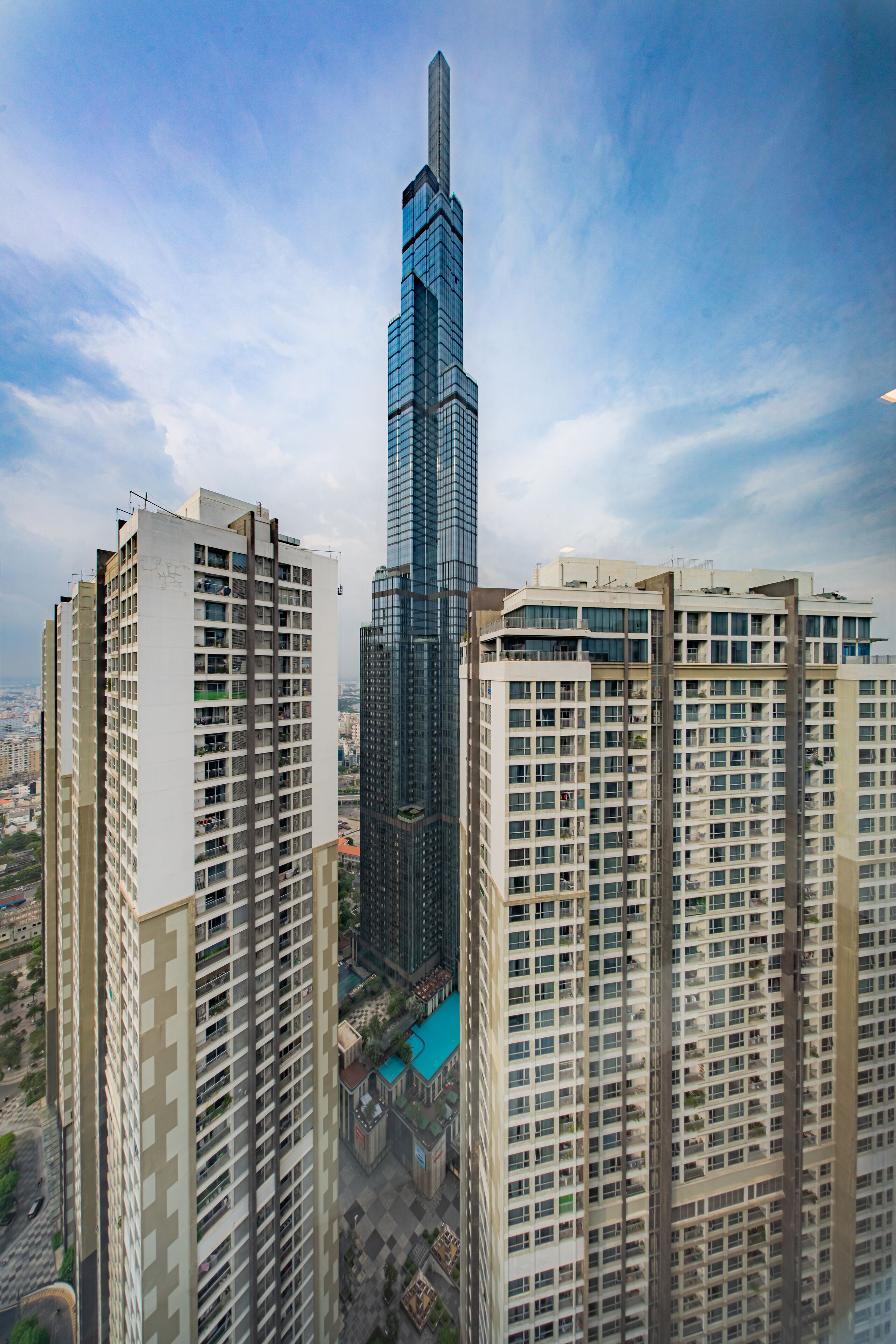 A high-rise building with a modern glass facade, surrounded by other residential buildings.