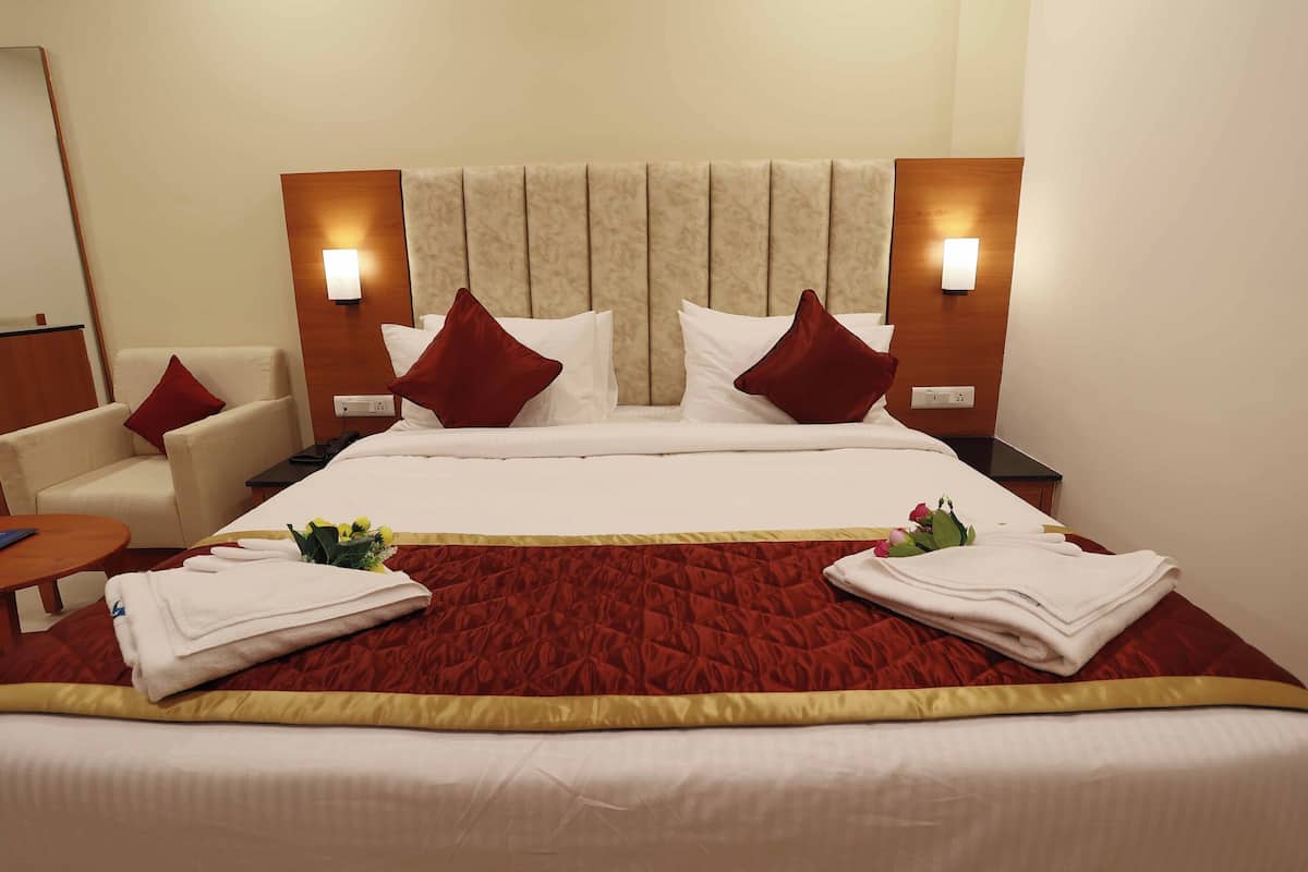 A hotel room with a large bed, two bedside tables, a chair, and a mirror.