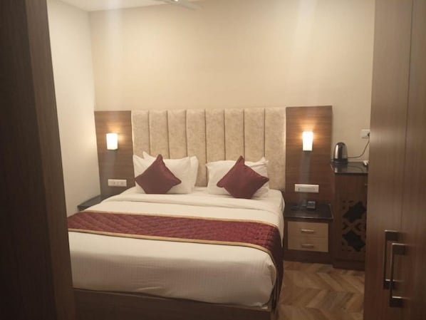 Una habitación de hotel con una cama, dos mesitas de noche y suelo de madera.