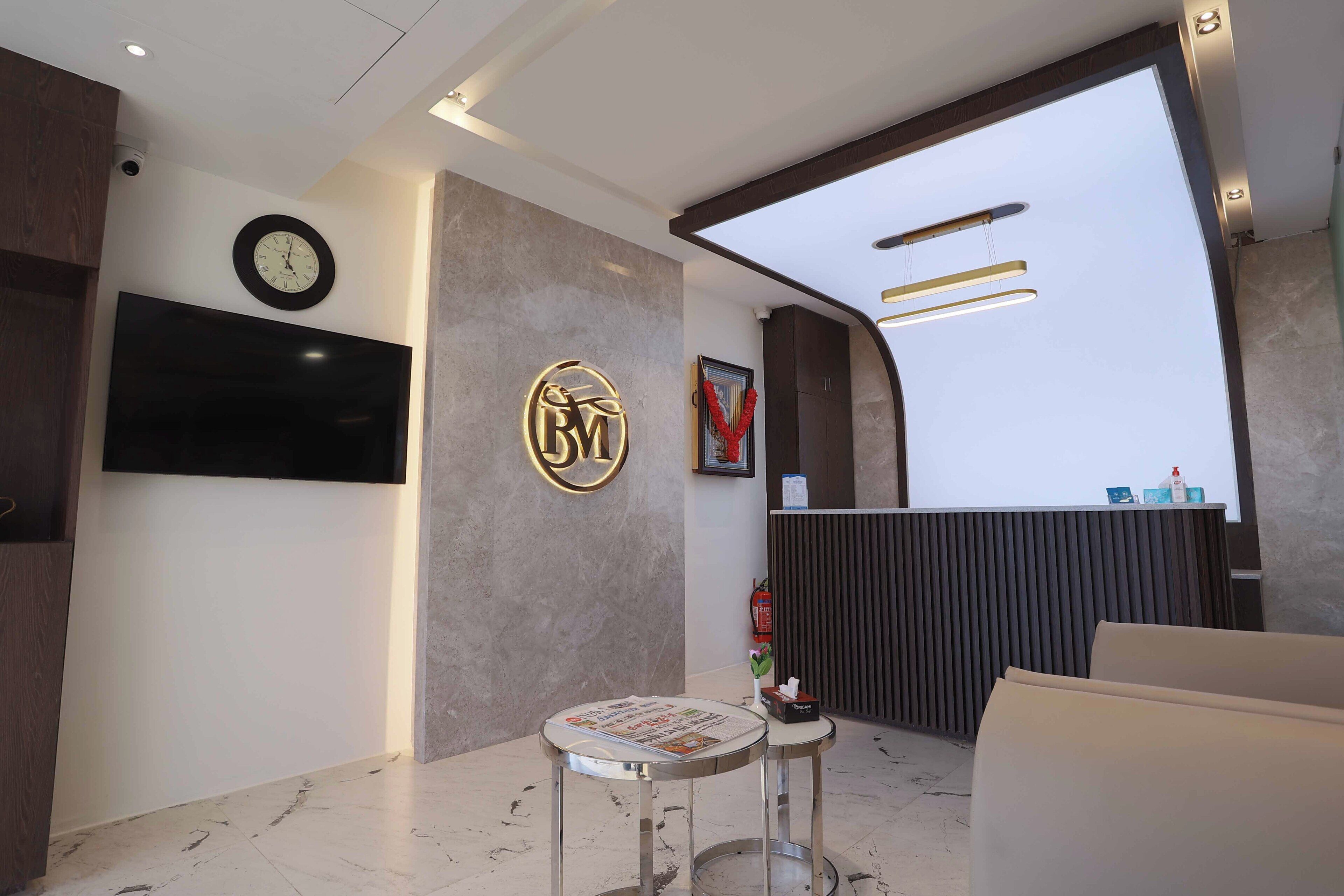A modern reception area with a marble floor, a clock, a reception desk, and a mounted television.