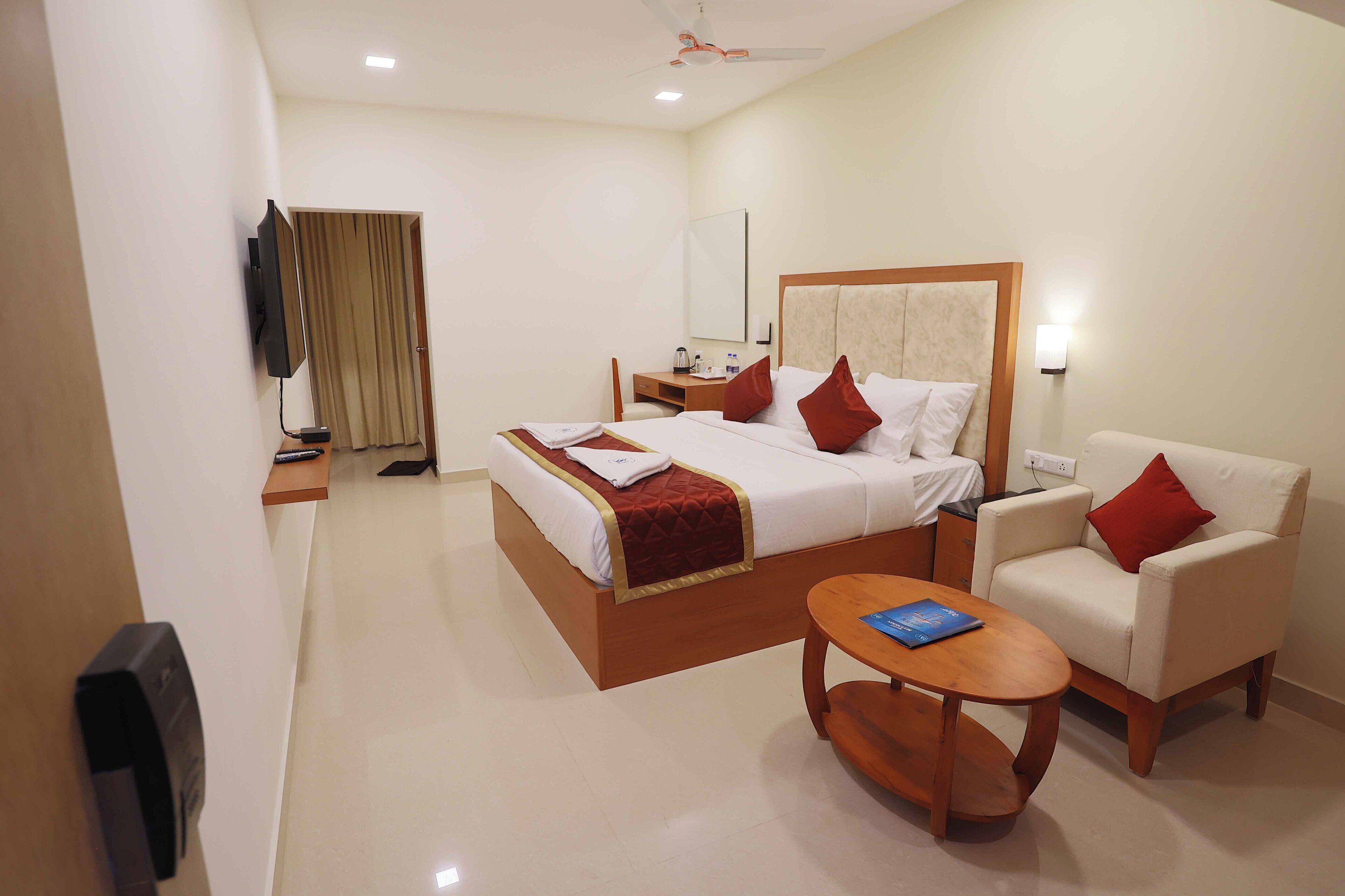 A hotel room with a bed, a desk, a chair, a TV, and a ceiling fan.