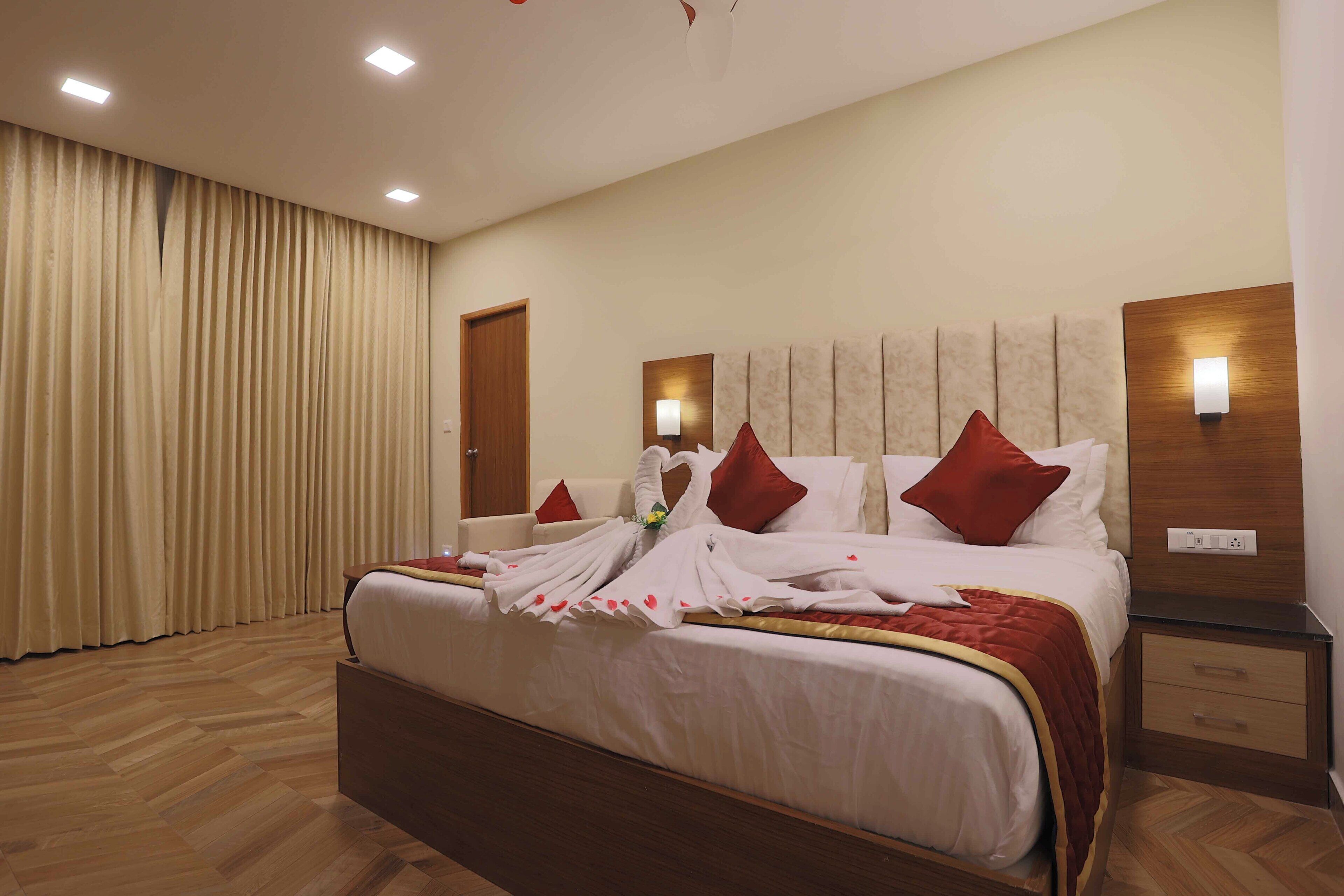 Habitación de hotel con una cama grande, cabecero de madera, dos mesitas de noche y suelo de madera.