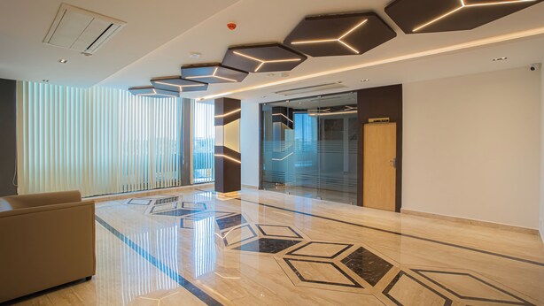 A modern lobby with a geometric floor design, a sofa, and a glass partition wall. - HOTEL BLUEMOON (Palayankottai)