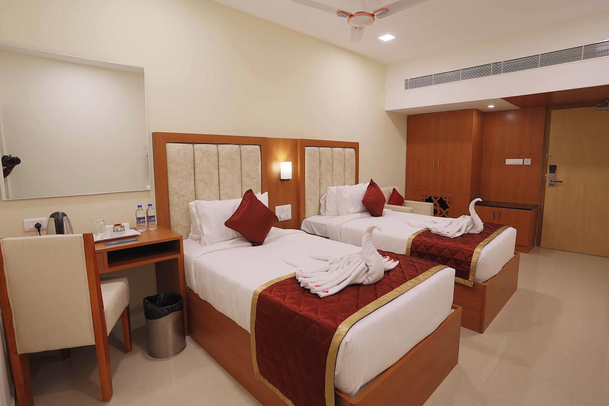 A hotel room with two beds, a desk, a trash bin, and a wardrobe.