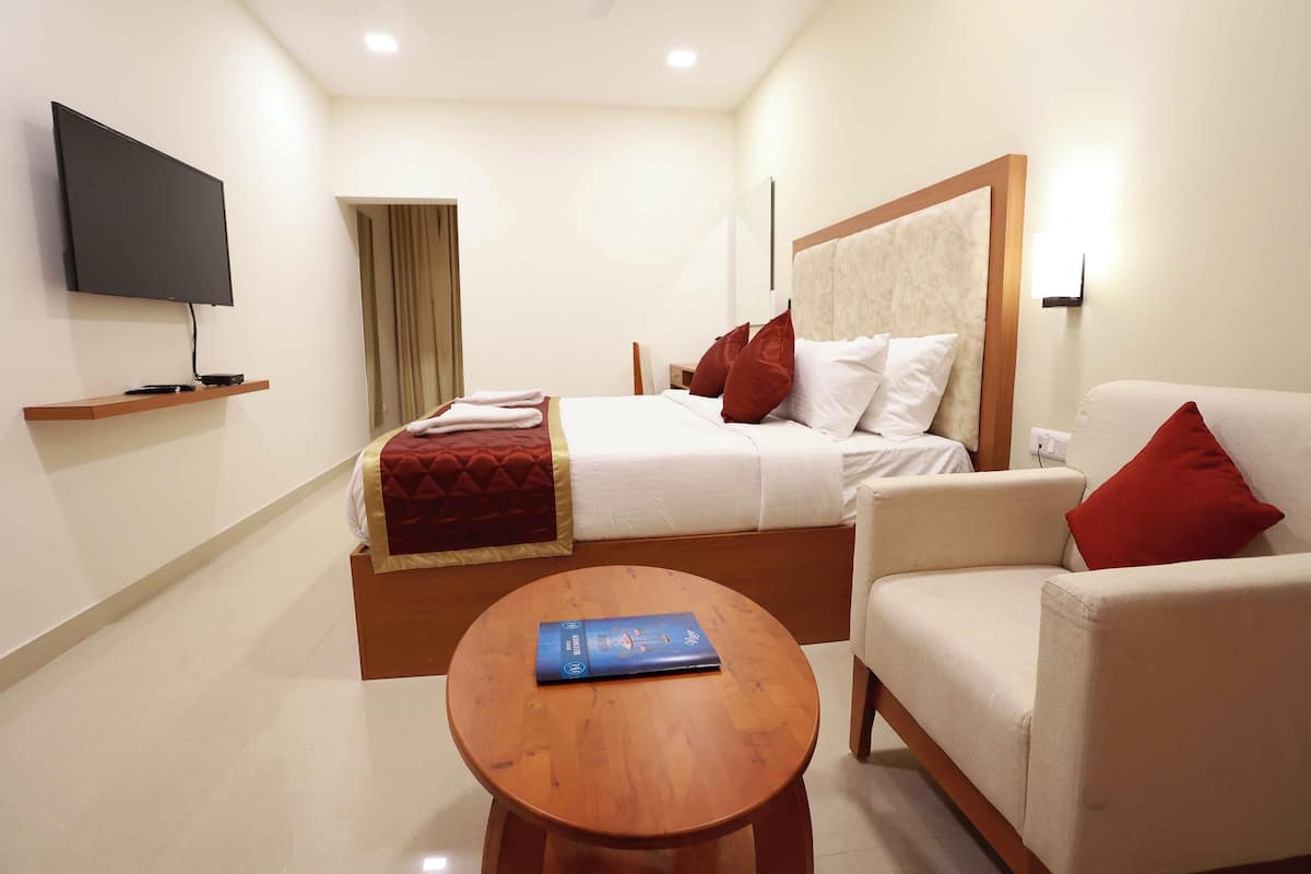 A hotel room with a bed, a sofa, a TV, and a table.