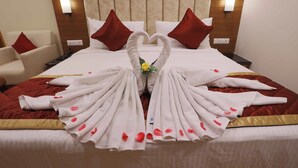 A hotel room with a neatly made bed, a chair, and a bedside table. - HOTEL BLUEMOON (Palayankottai)