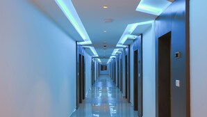 A long, narrow hallway with a reflective floor and blue lighting along the ceiling. - HOTEL BLUEMOON (Palayankottai)