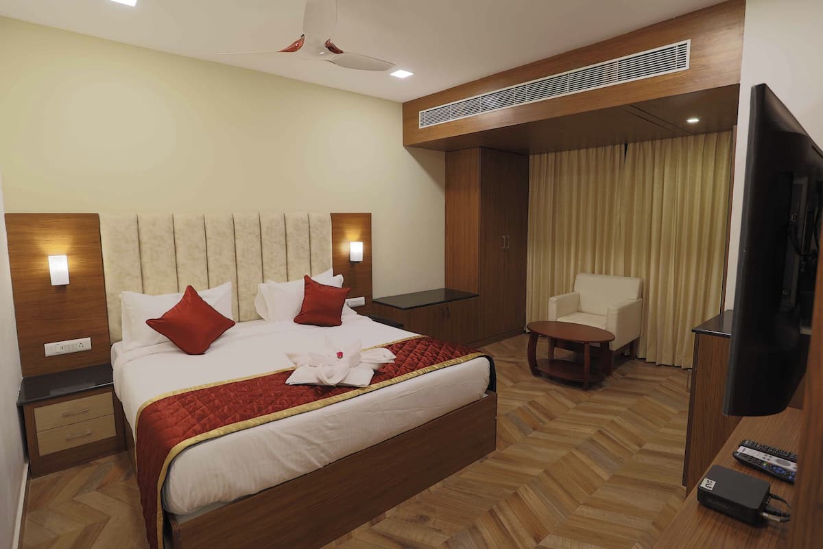 A hotel room with a large bed, a TV, a desk, and a chair.