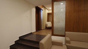 A modern interior with a staircase, a sofa, and a wooden panel wall. - HOTEL BLUEMOON (Palayankottai)