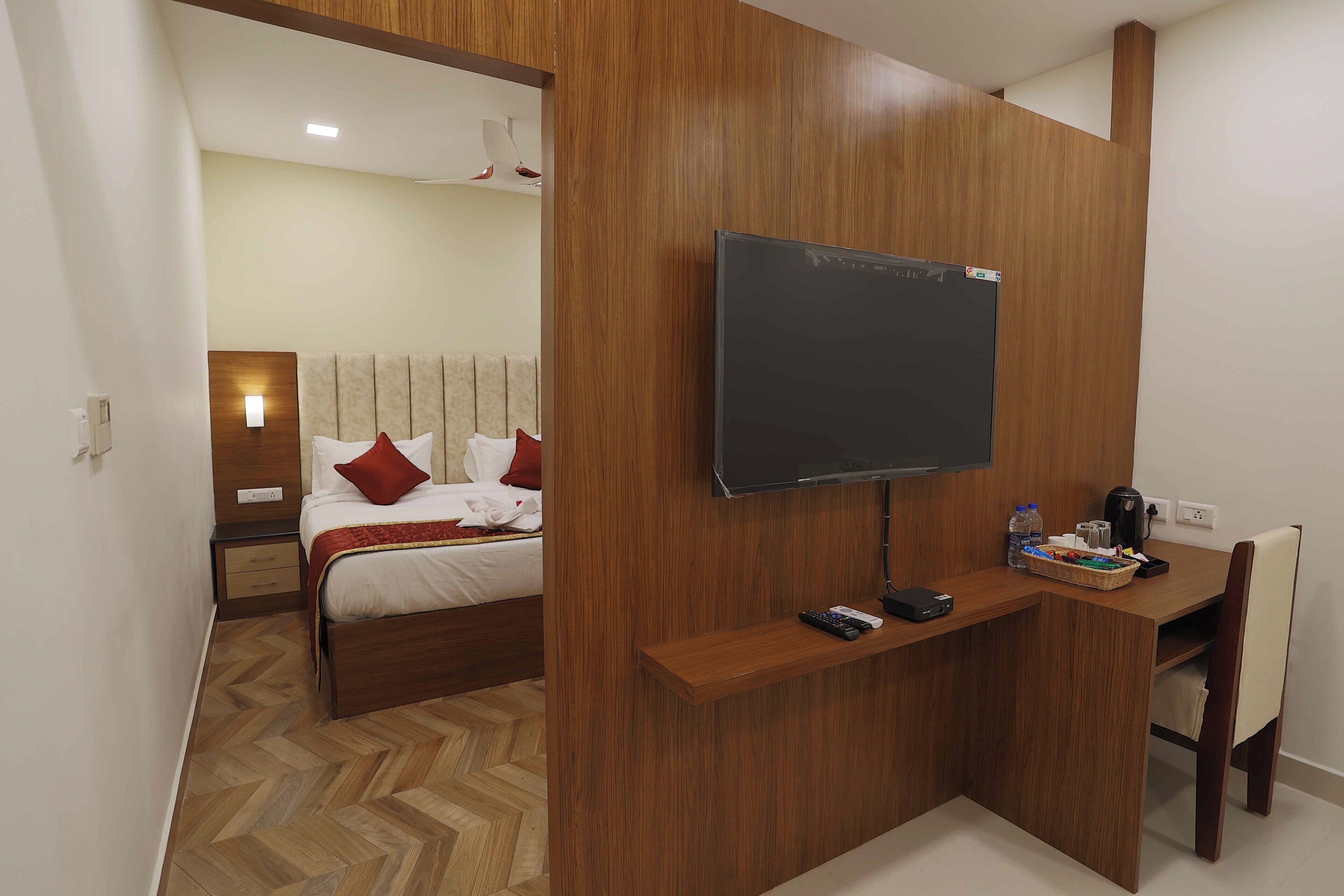 A hotel room with a bed, a desk, a television, and a chair.