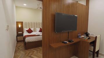 A hotel room with a bed, a desk, a television, and a chair.