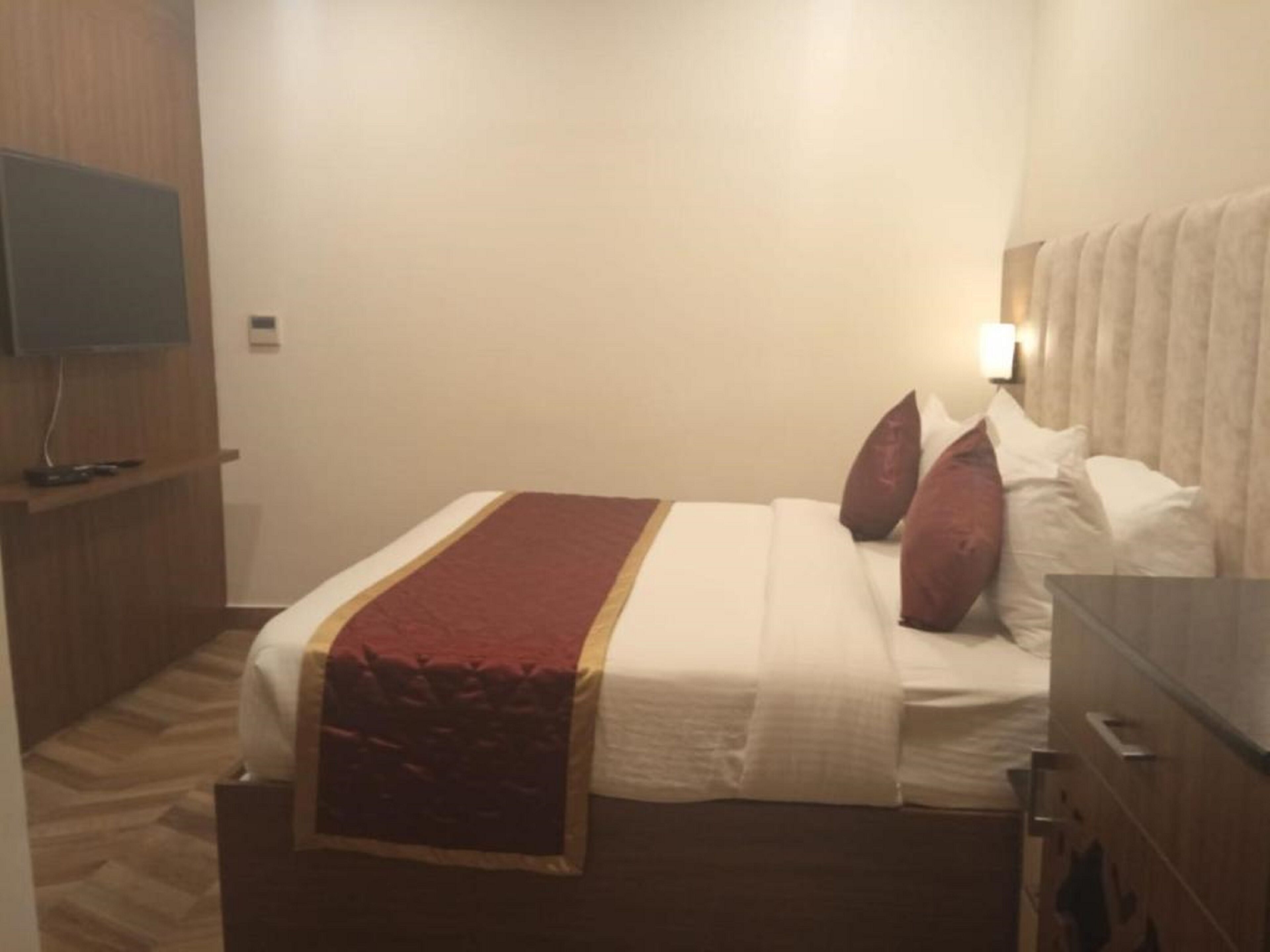 Habitación de hotel con cama, televisor montado en la pared y suelo de madera.