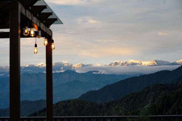 Paisaje montañoso con una pérgola de madera y luces colgantes.