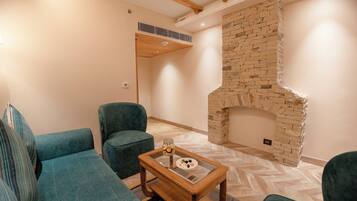 Una sala de estar con chimenea de piedra, sofás color turquesa y una mesa de centro de madera con superficie de vidrio.