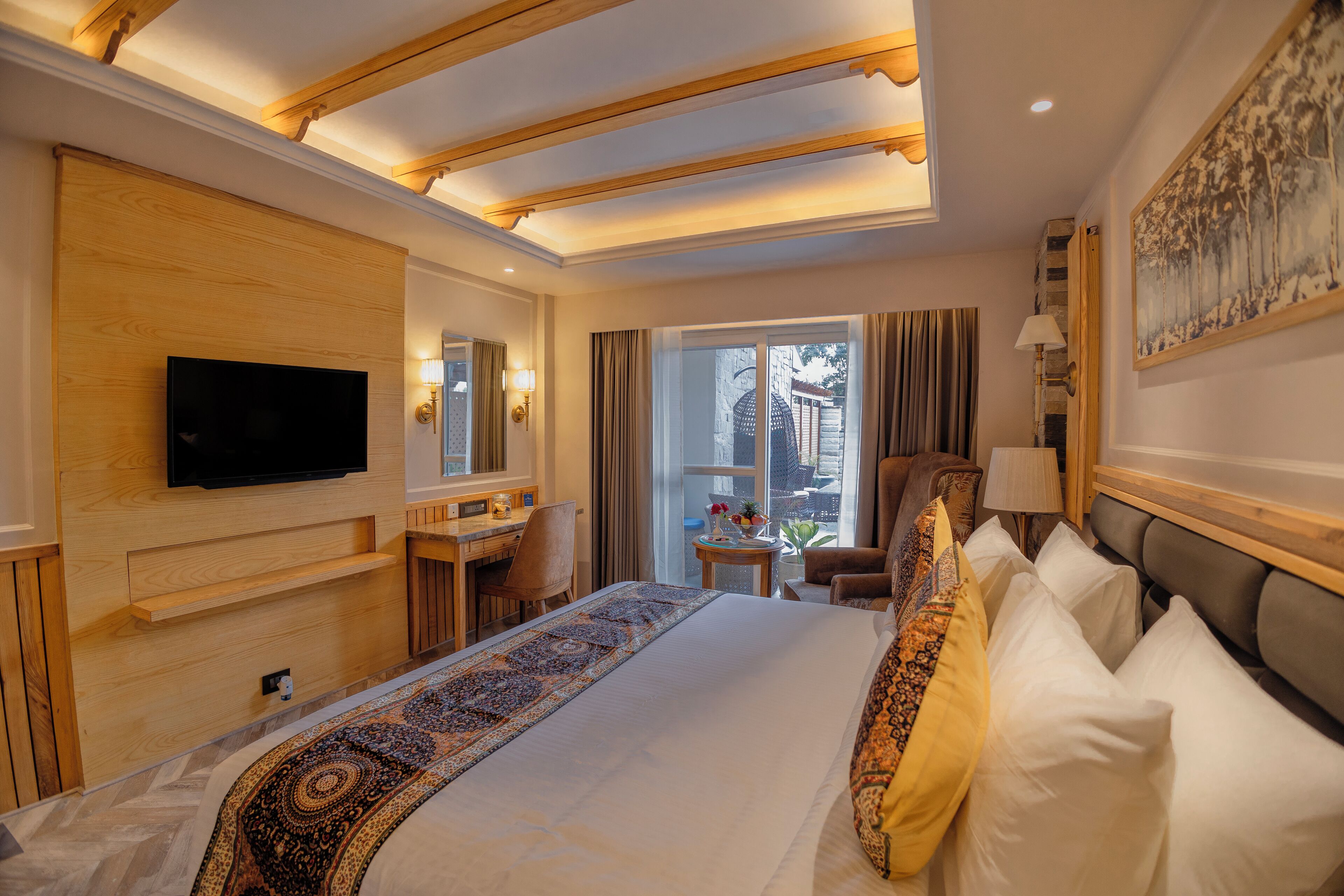 A hotel room with a large bed, a TV mounted on the wall, a desk, and a chair.