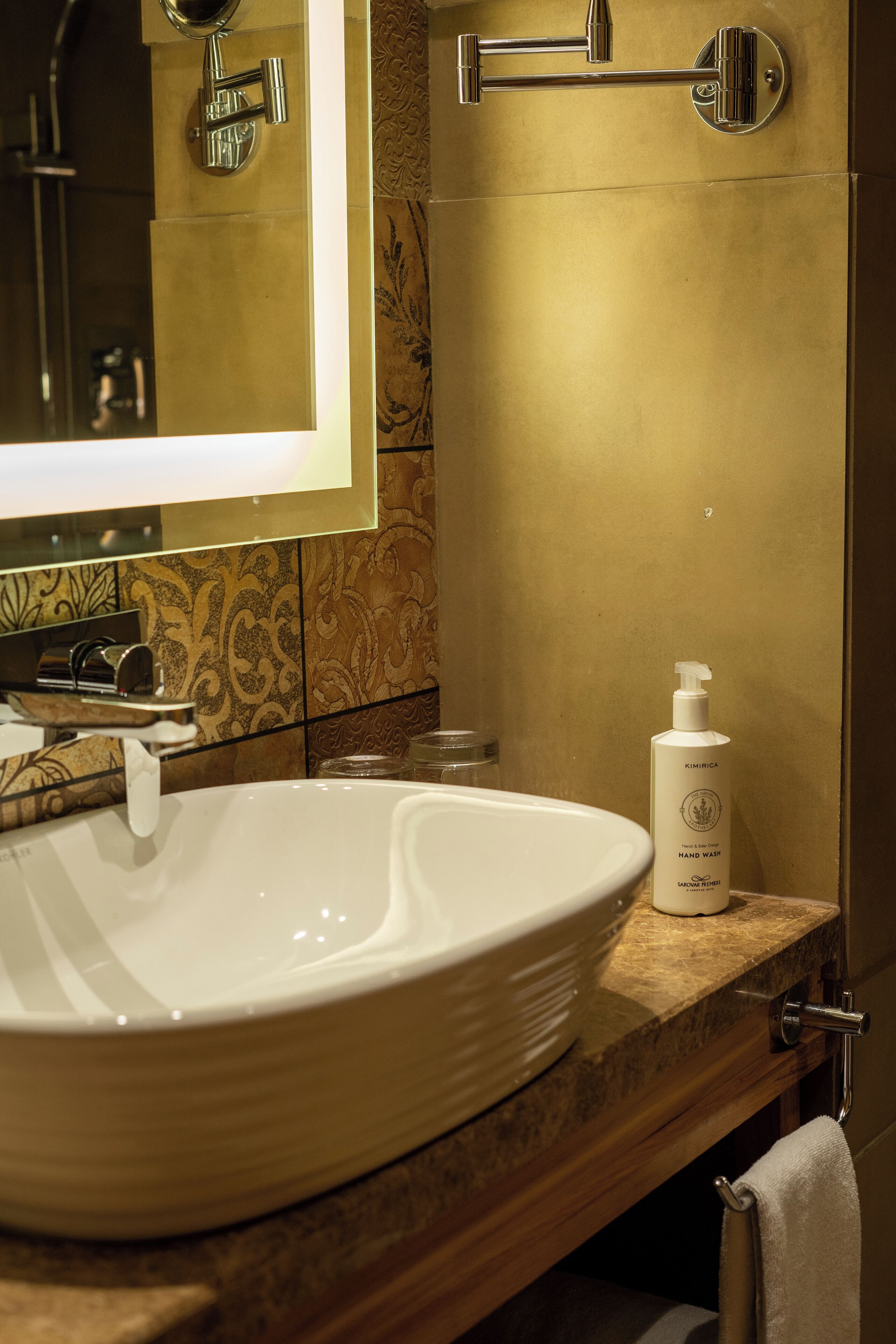 A bathroom with a large white sink, a handheld showerhead, and a bottle of hand wash soap on the vanity.