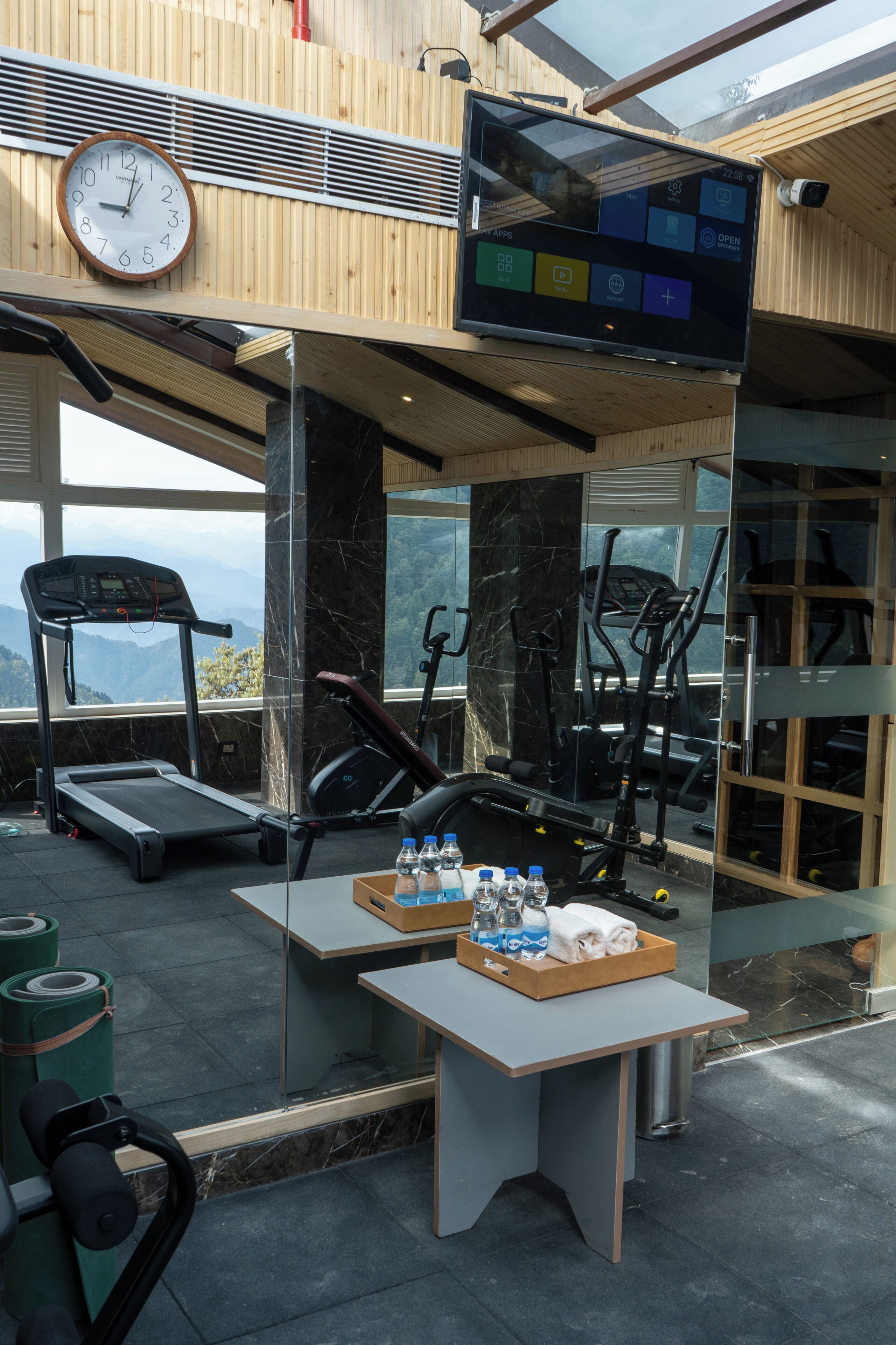 Een sportschool met trainingsapparatuur, een klok en een scherm waarop apps worden weergegeven.