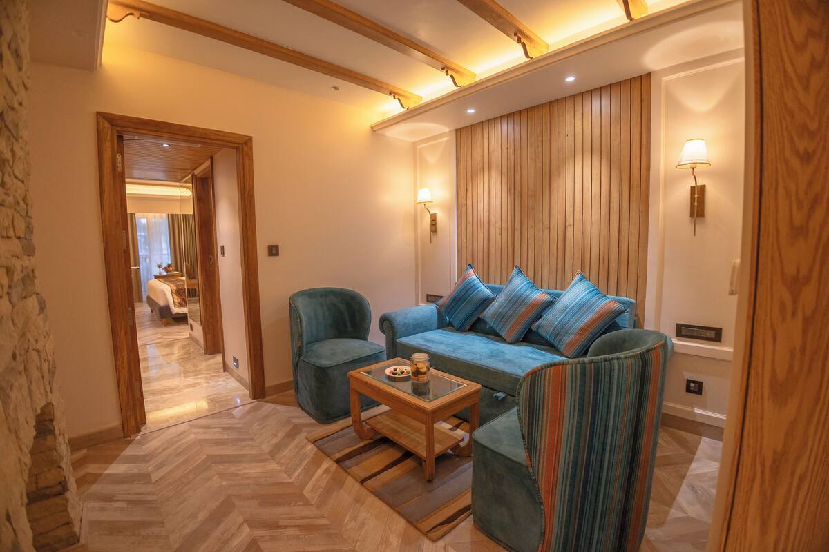 A modern living room with a herringbone-patterned floor, a blue sofa with striped cushions, a striped armchair, and a glass coffee table.