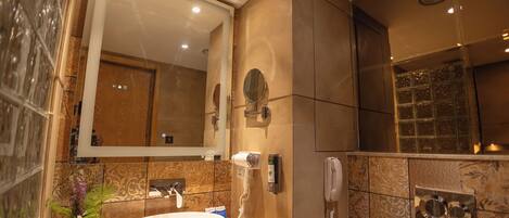 A modern bathroom with a large mirror, a round sink, and a handheld hair dryer.