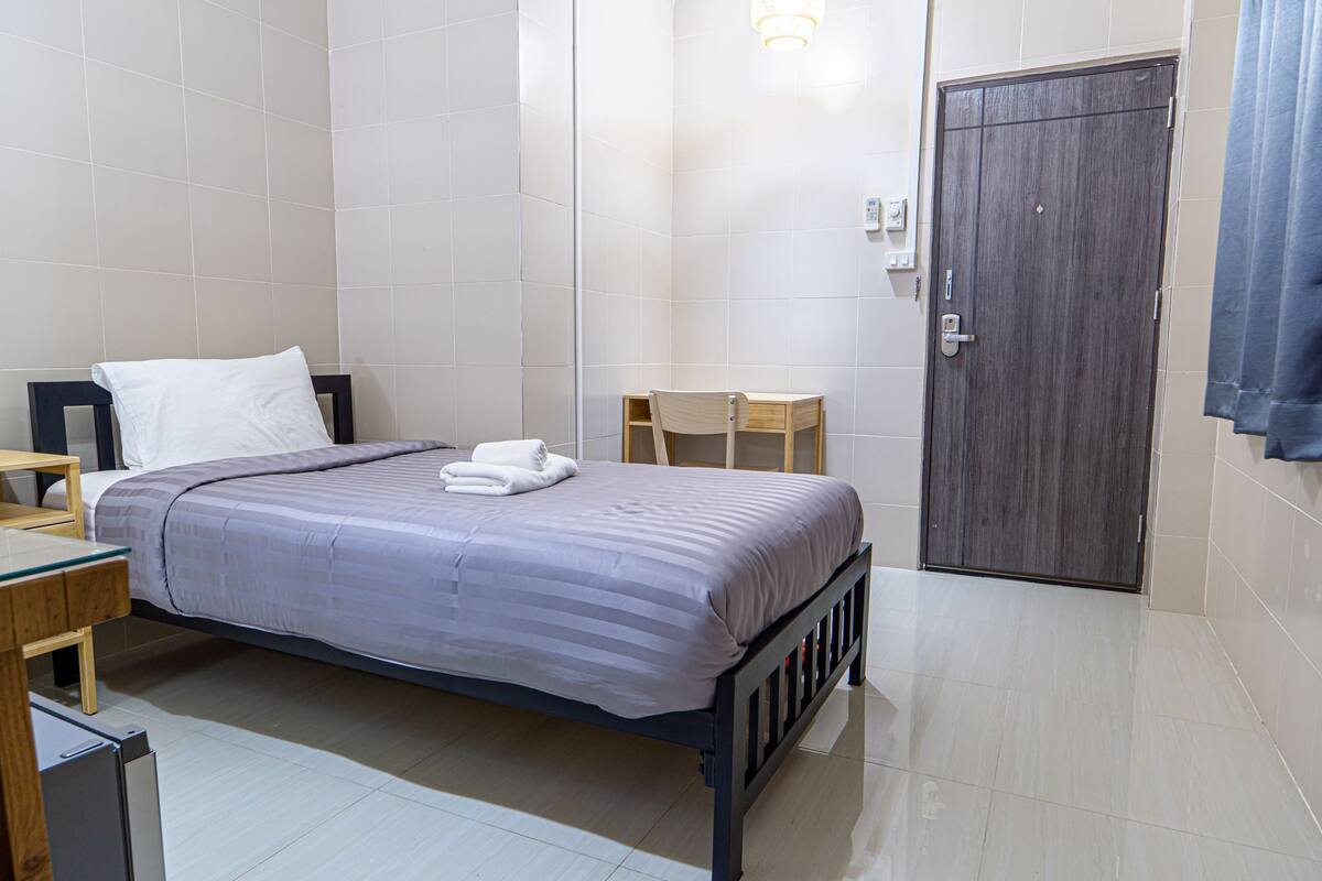 A neatly arranged bedroom with a bed, bedside table, and a small wooden chair.