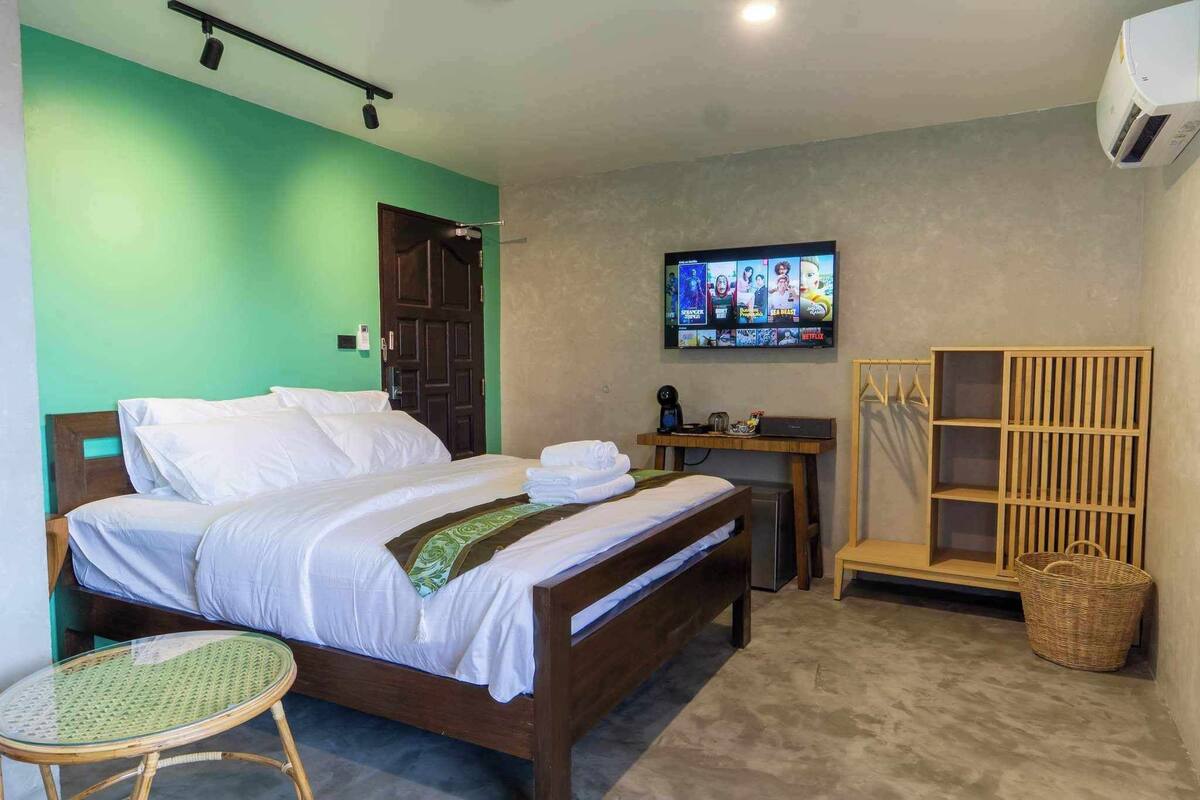 A hotel room with a bed, a television, a desk, and a wardrobe.