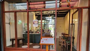 A restaurant with a wooden exterior, large glass windows, and a menu stand outside. - Lo-ha Guesthouse Contactless Check-in (Bangkok)