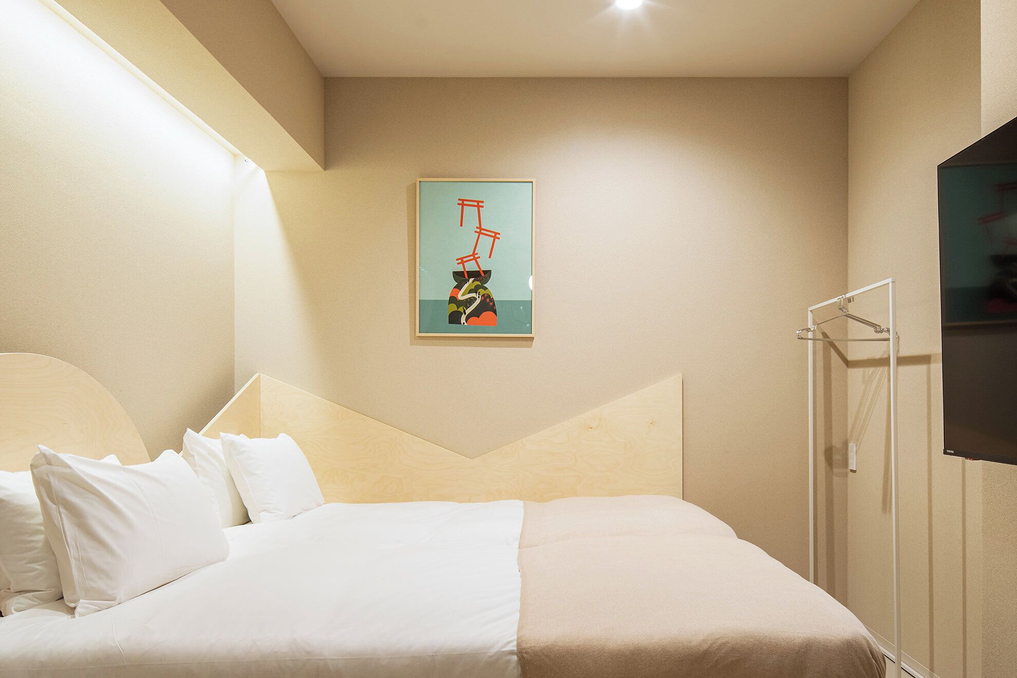 Een hotelkamer met een bed, douche en een tv aan de muur.