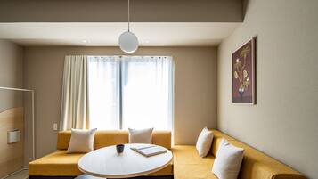 A modern living room with a sofa, a round table, and a painting on the wall.
