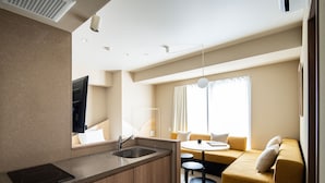 A modern hotel room with a kitchen area, a sofa, and a dining table. - Section L Yushima - Ueno (Tokyo)