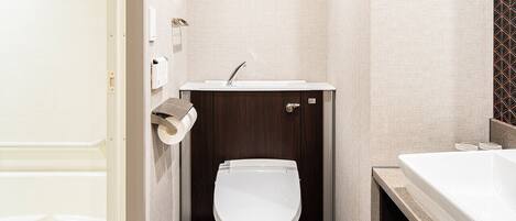 A compact bathroom with a toilet, sink, and shower area.