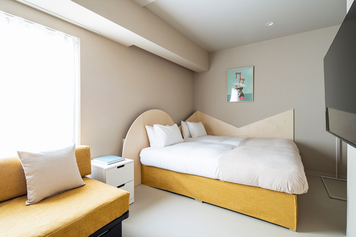 A modern hotel room with a bed, a bedside table, a chair, and a TV.