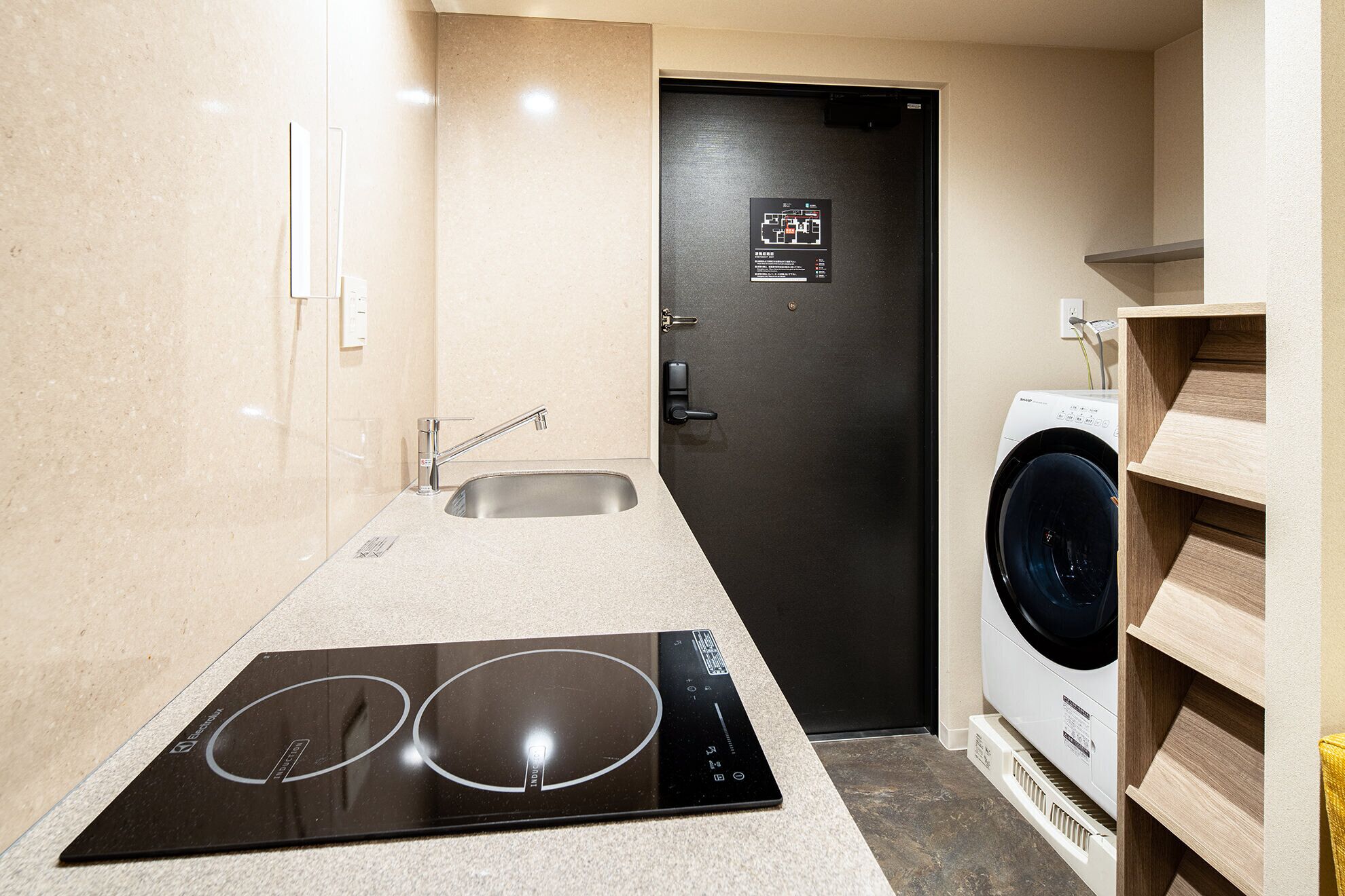 A compact kitchenette with an induction cooktop, a sink, and a washing machine.