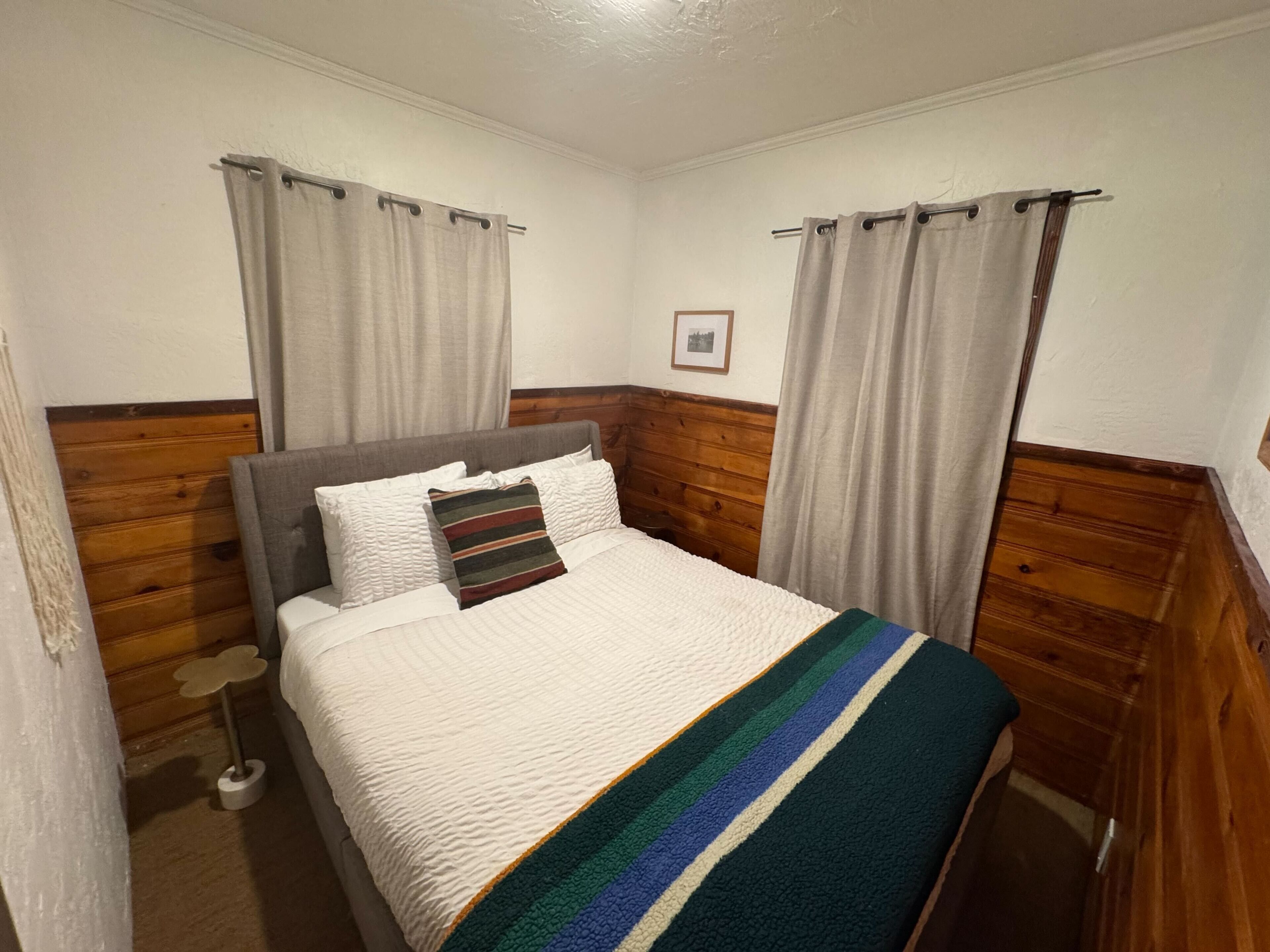 Una cama bien hecha con un edredón a rayas, almohadas blancas y un cabecero de madera.