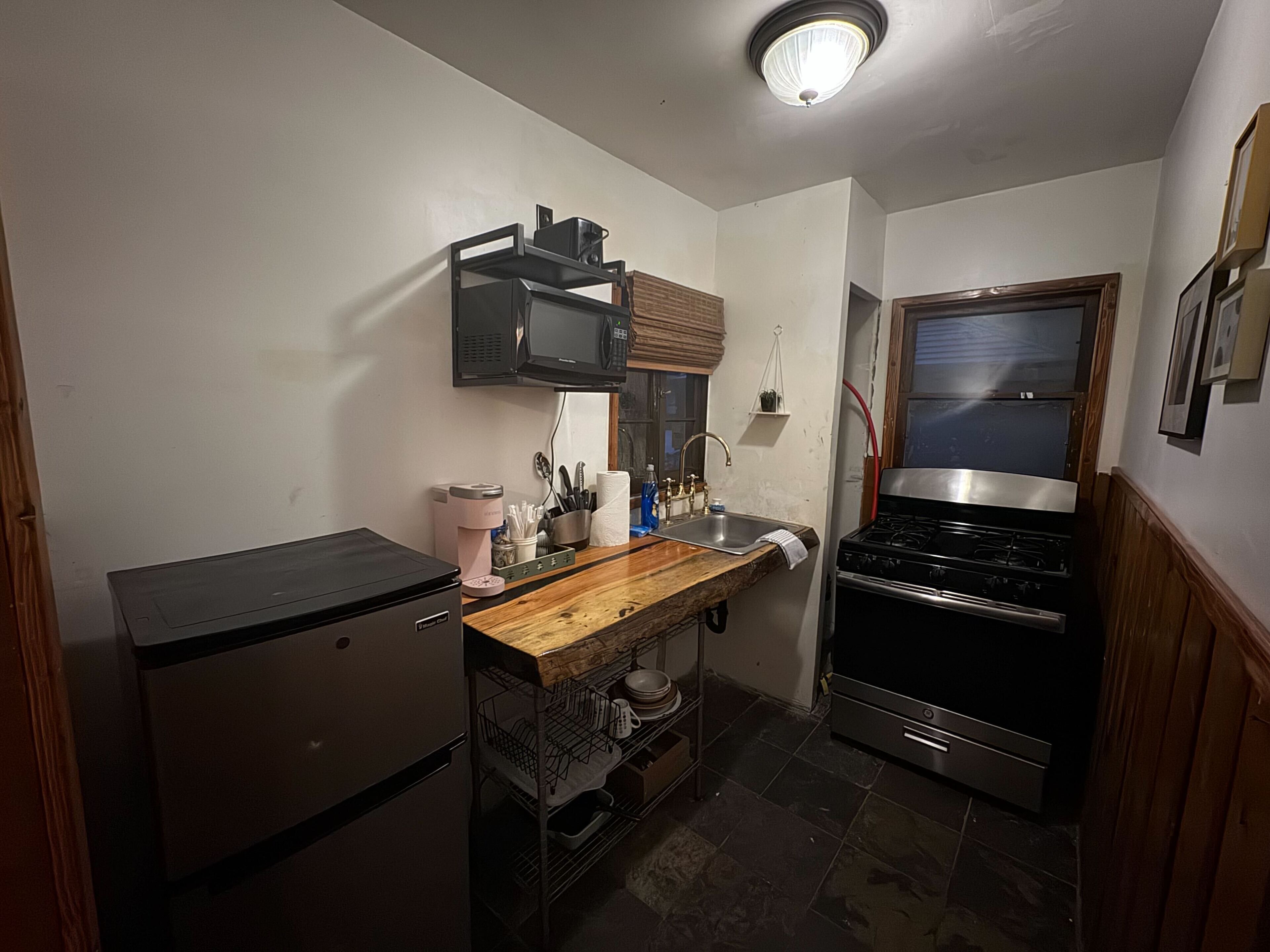 A compact kitchen with a refrigerator, microwave, sink, and stove.