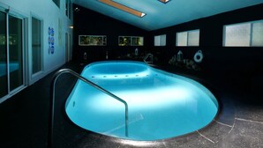 Una piscina con fondo de cristal, rodeada por un interior oscuro con ventanas y suelo de baldosas.