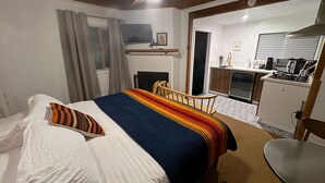 Un dormitorio con cama, escritorio y kitchenette.