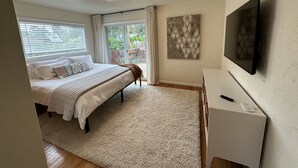 Une chambre à coucher avec un lit, une télévision, un tableau et une fenêtre avec des stores.