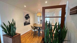 Un espace repas moderne avec une table et des chaises en bois, un tableau au mur et des plantes en pot.
