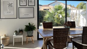 Un comedor con sillas de mimbre, una mesa de madera y obras de arte enmarcadas en la pared.