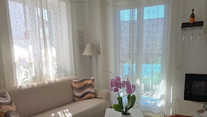 Ein Wohnzimmer mit einer Couch, einem Couchtisch mit Pflanze und einem Fernseher auf einem Schrank.