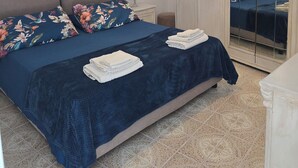 Ein Schlafzimmer mit Bett, Kissen, Nachttisch, Lampe, Spiegel und Kleiderschrank.