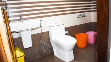 A bathroom with a striped tile wall, a white toilet, a sink, and two buckets.