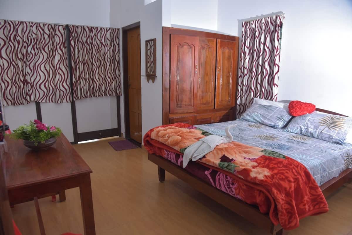 Un dormitorio con una cama de madera, un armario de madera y una mesa de madera con una planta en maceta.